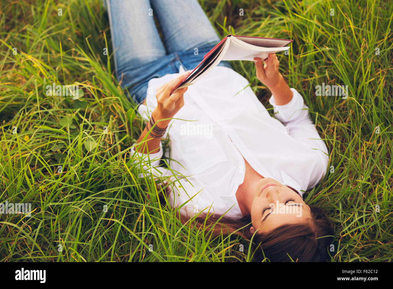 Young Woman Enjoying a Book Reading Outdoors Stock Photo