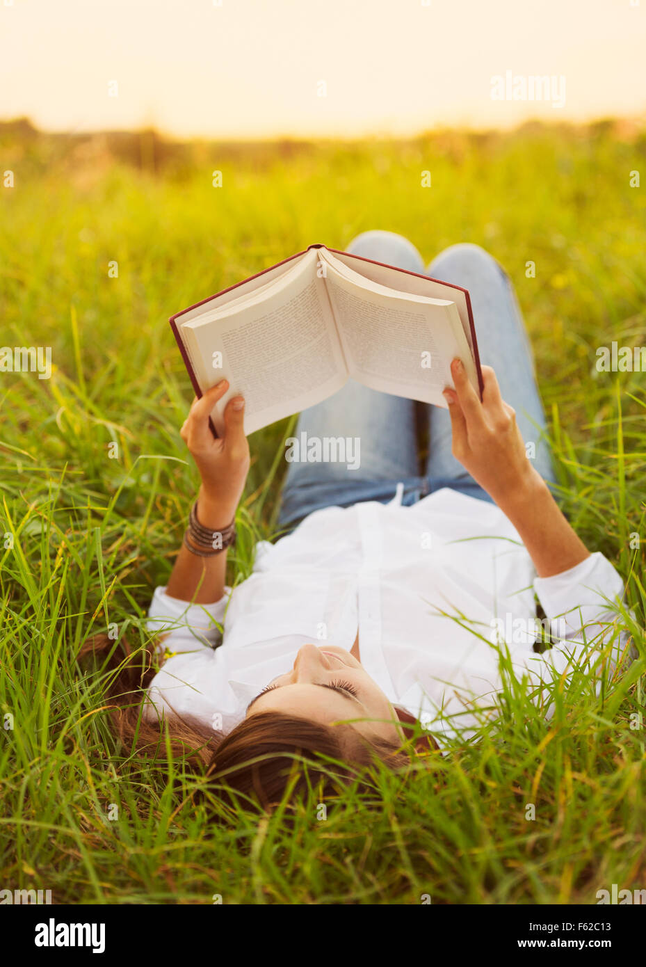 Young Woman Enjoying a Book Reading Outdoors Stock Photo