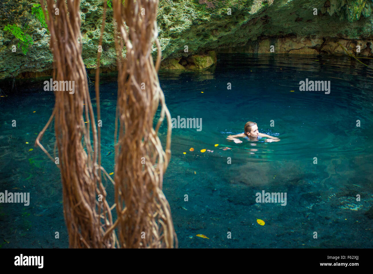 Woman enjoys a refreshing swim in a cenote in Yucatan, Mexico. Stock Photo