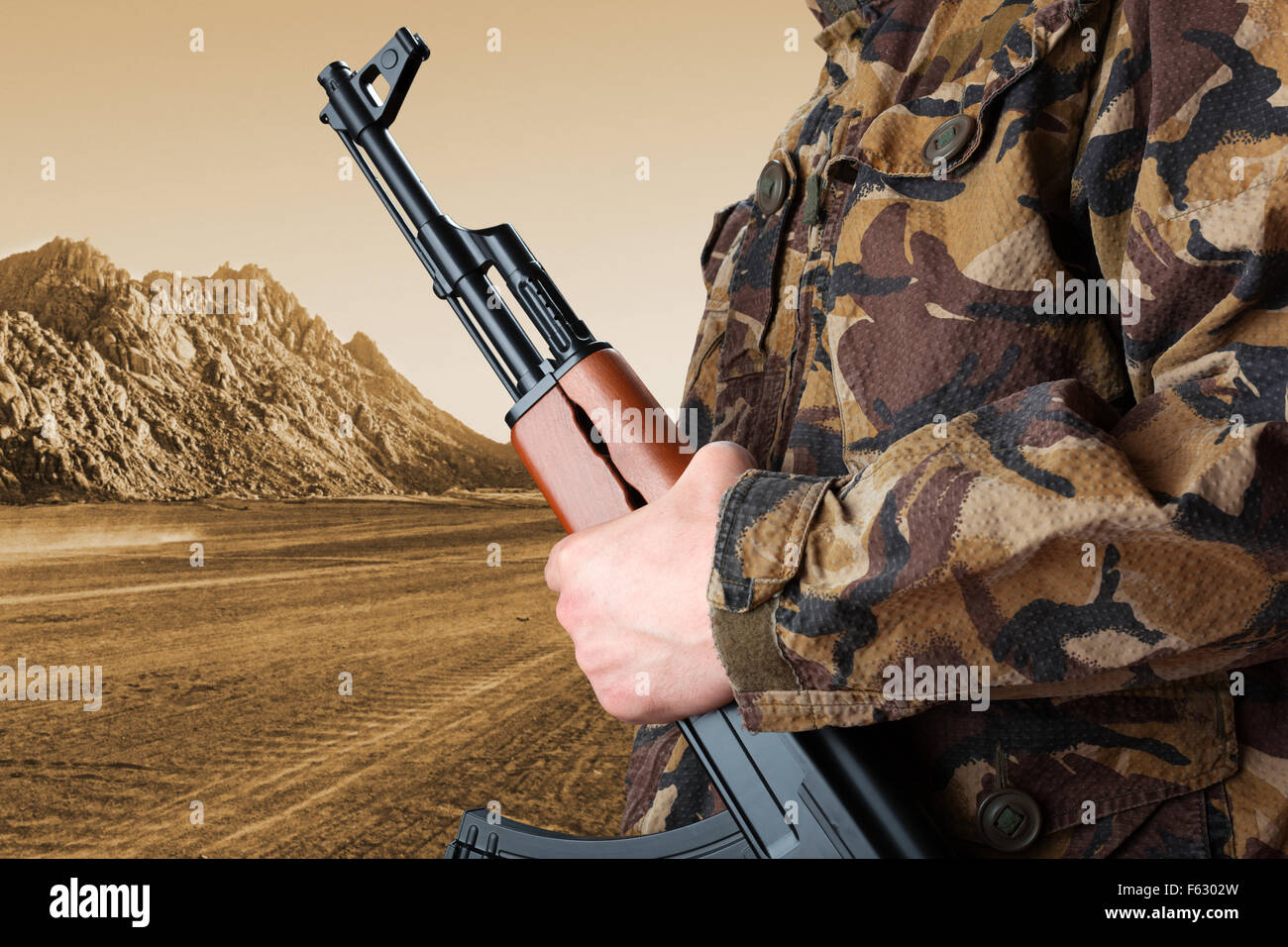 Soldier holding rifle AK-47 against desert Stock Photo