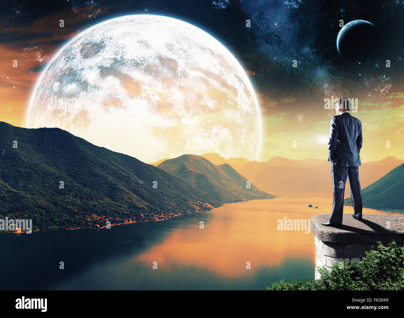 Businessman standing on the edge in the night and looking at the big moon Stock Photo