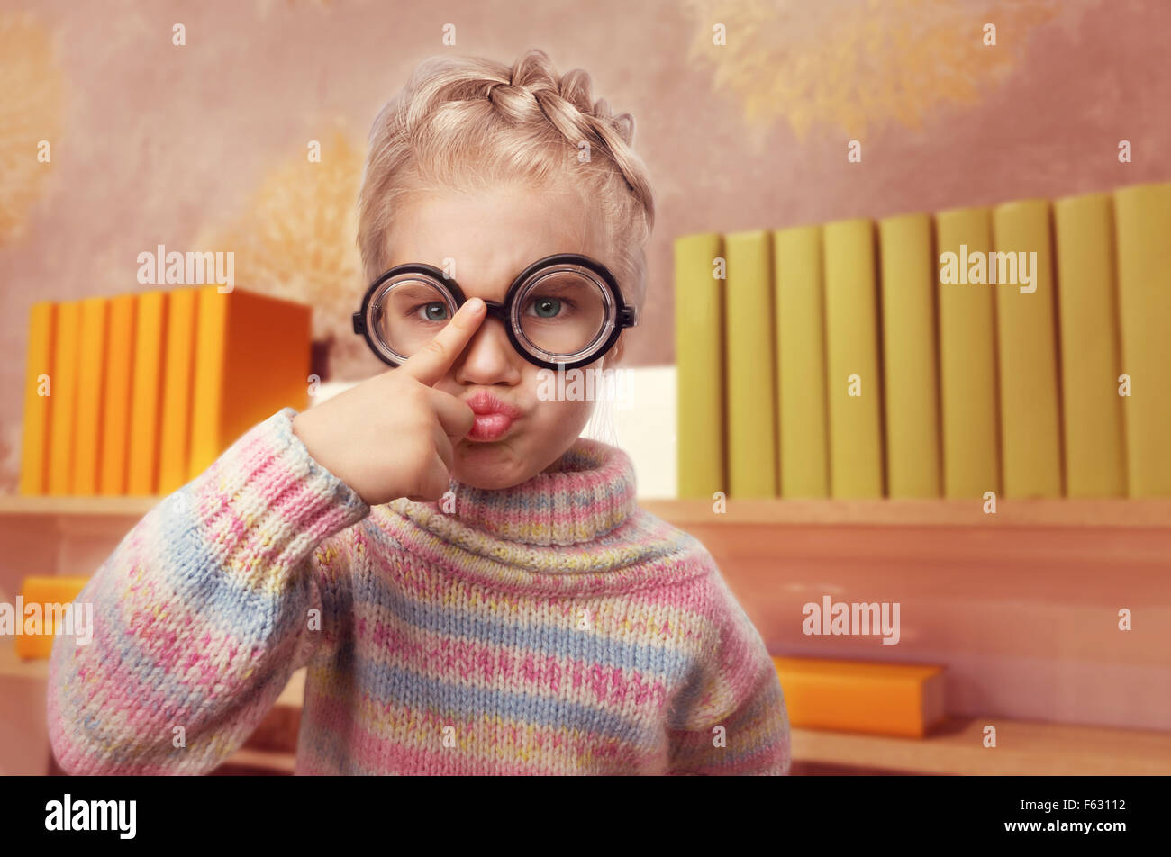 Little egghead girl in glasses makes faces in home interior Stock Photo