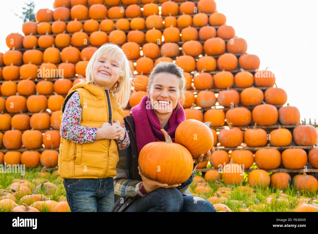 A beautiful smiling woman and cute little girl holding pumpkins in ...