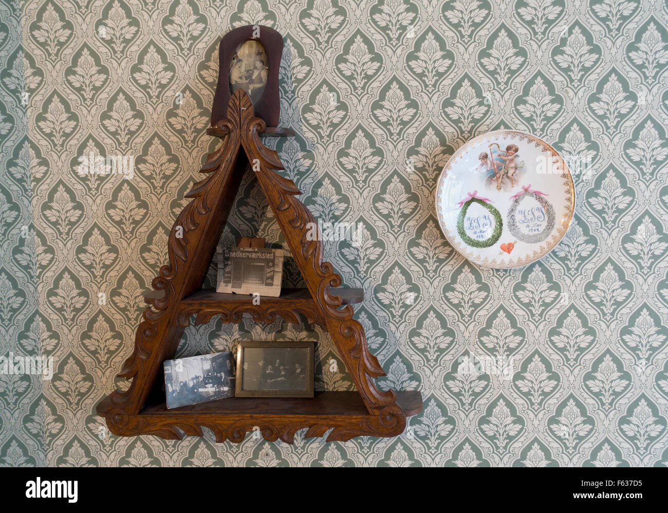 Old triangular shelf with family and small carpenter business photos beside a silver wedding plaque. Workers Museum, Copenhagen. Stock Photo