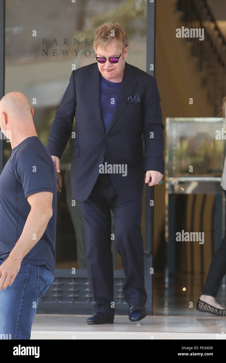 Elton John holds the door for a lady as he exits Barneys of New York