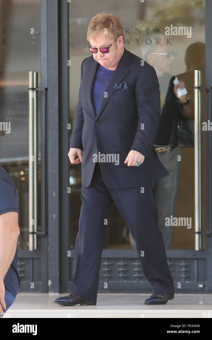Elton John holds the door for a lady as he exits Barneys of New York