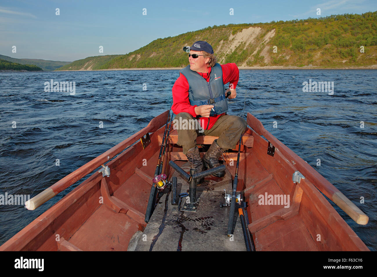 Salmon fishing guide driving his traditional handmade boat at Teno (Tana) River, on the border of Finland and Norway. Stock Photo