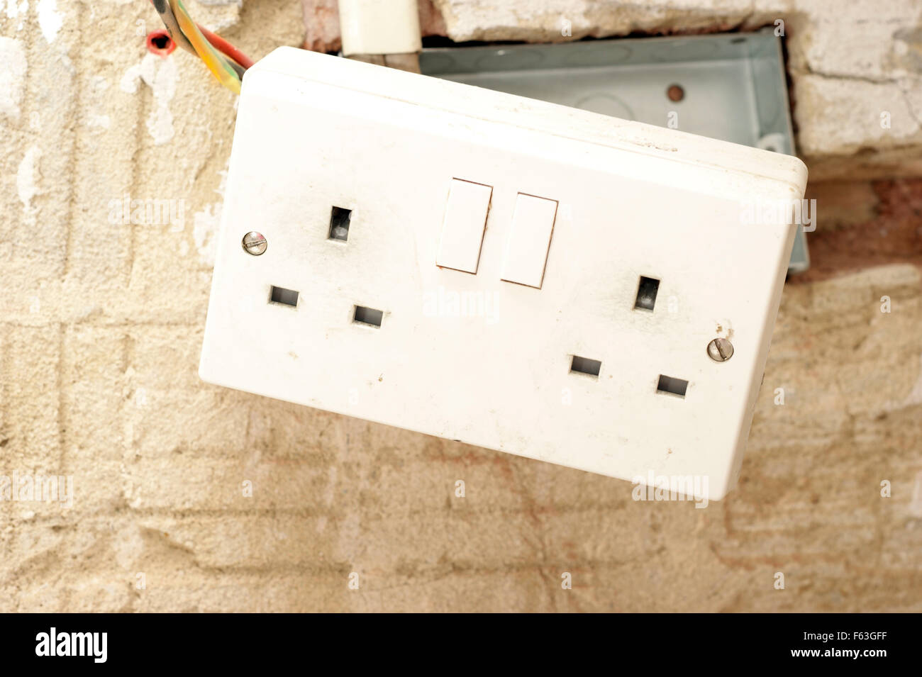 Electric plug sockets with exposed wiring in a rented social housing property house that needs attending to Stock Photo