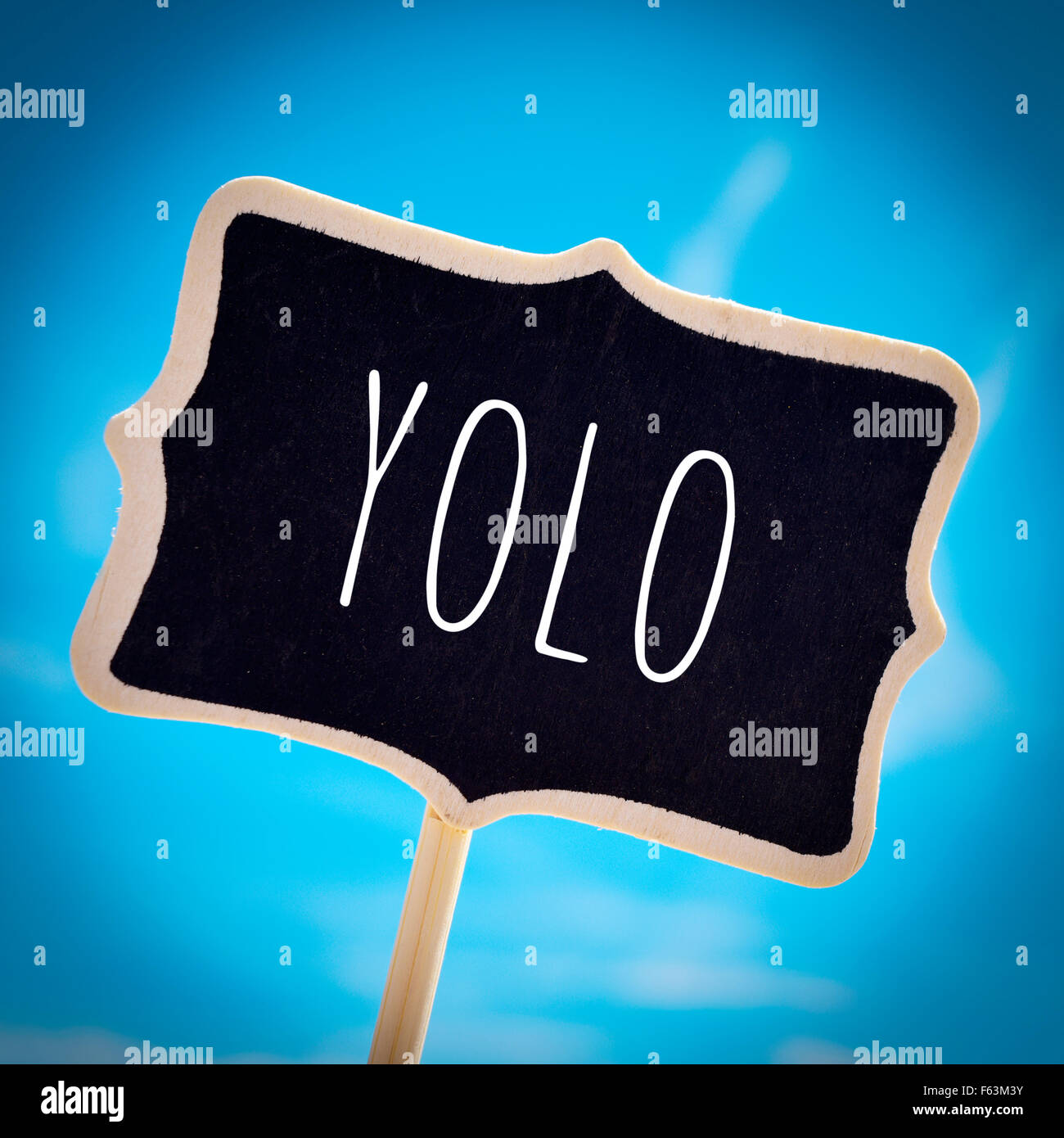 closeup of a signboard with the word yolo, for you only live once, over the blue sky, with a slight vignette added Stock Photo