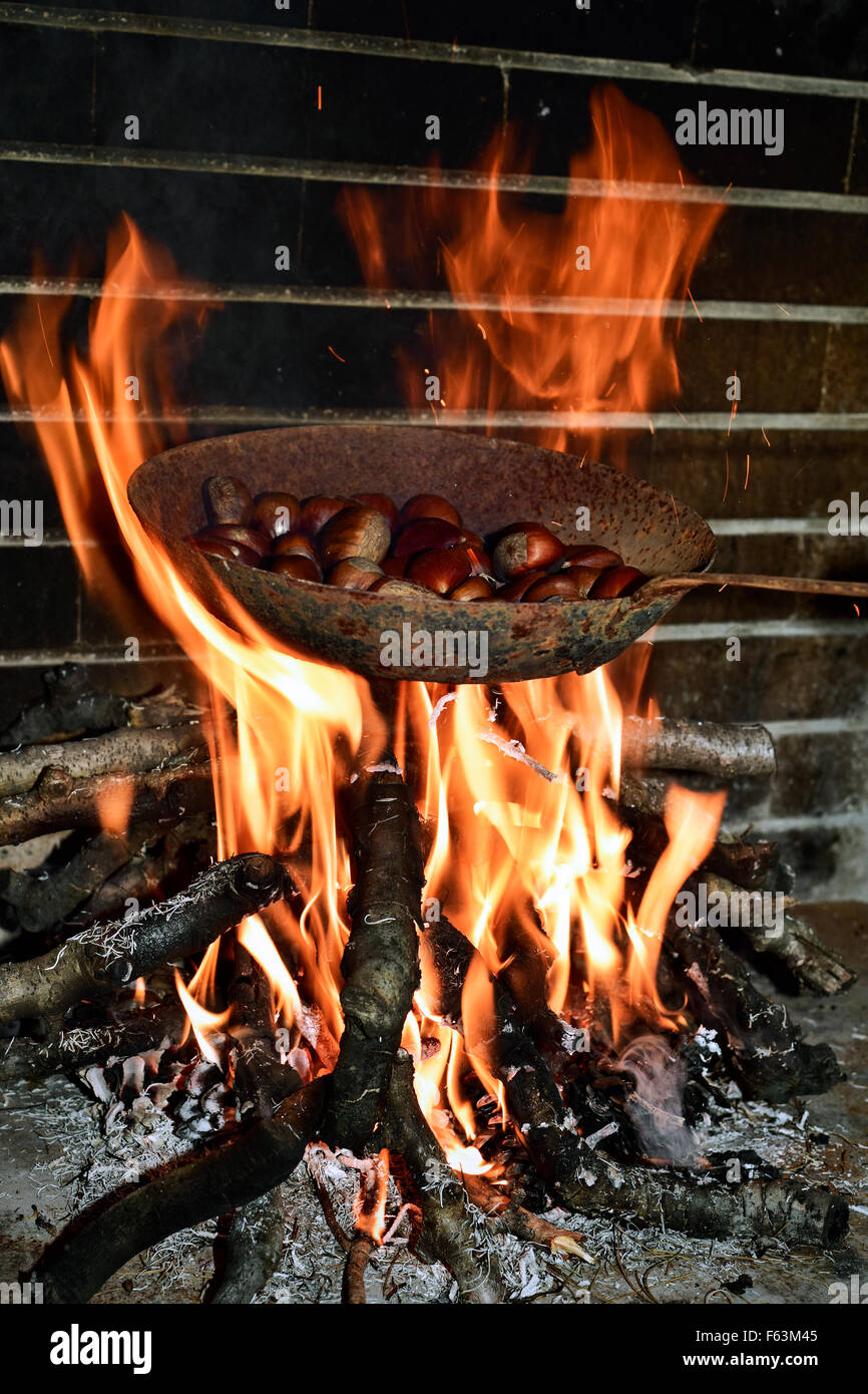 A frying pan over an open fire, with blackened fresh roasted chestnuts.  Stock Photo by Mint_Images