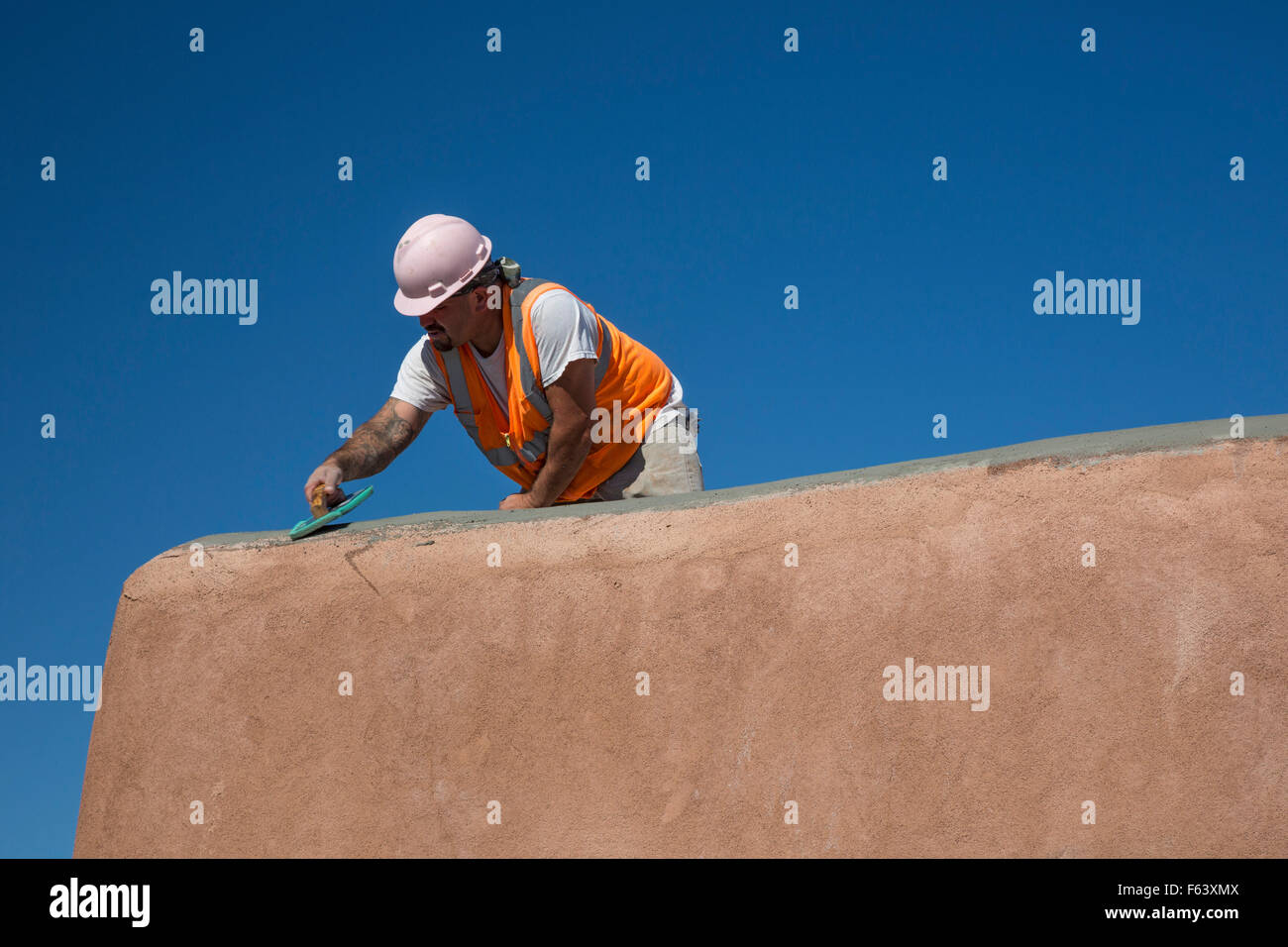 Alamogordo, New Mexico - A worker repairs an adobe building at the visitor center of White Sands National Monument. Stock Photo