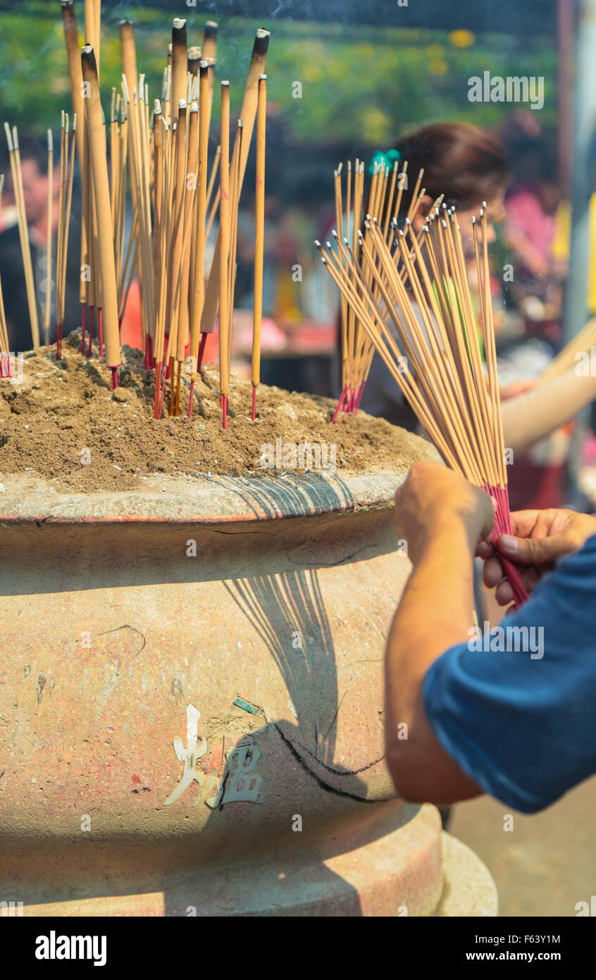 Chinese people put joss stick into incense furnace at Kwong Tong
