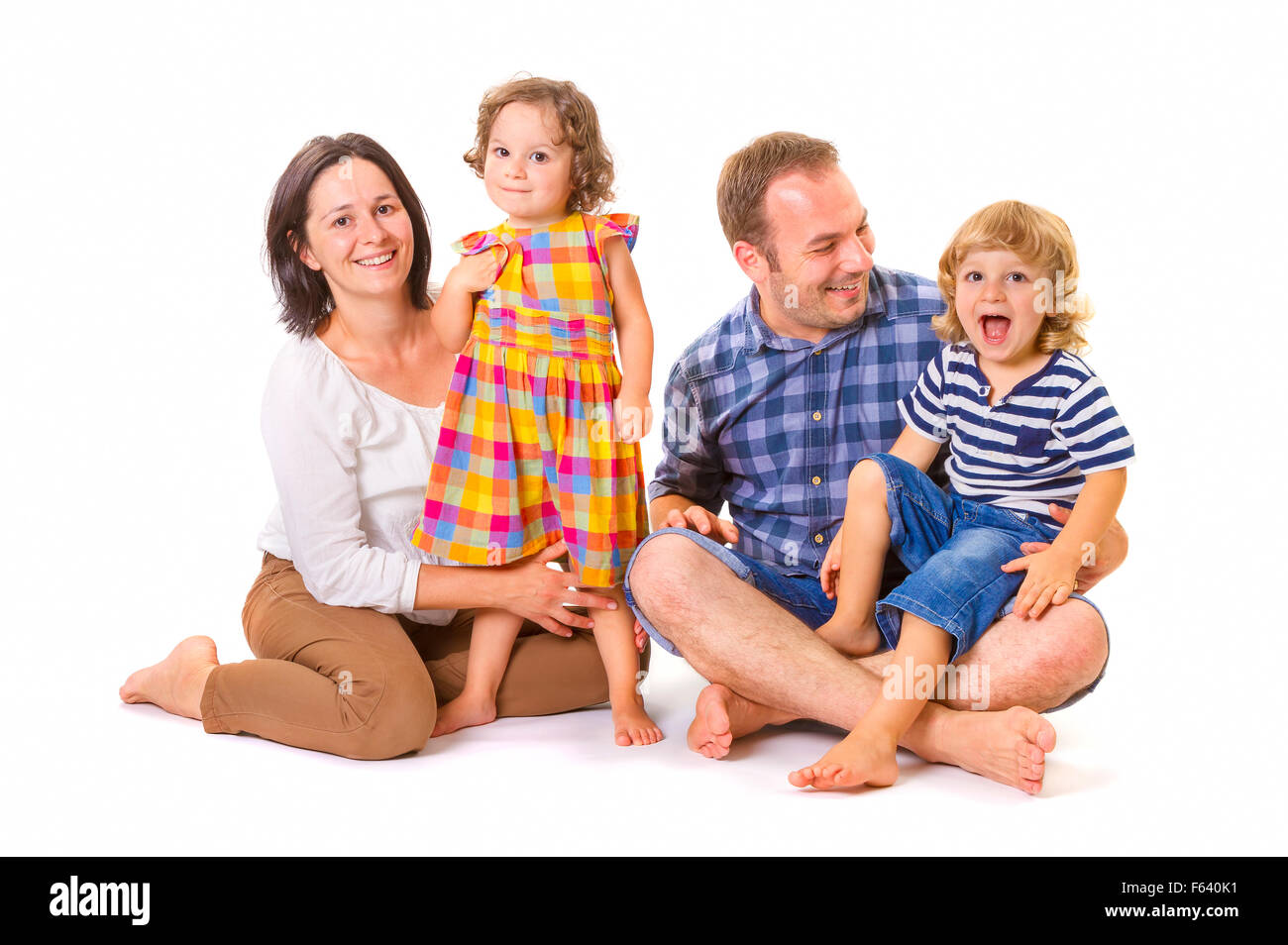 Happy family of four smiling while standing against white background. Stock Photo