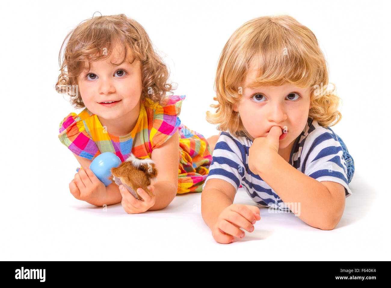 Funny boy and girl are lying together isolated on white background. Focus on little boy. Stock Photo