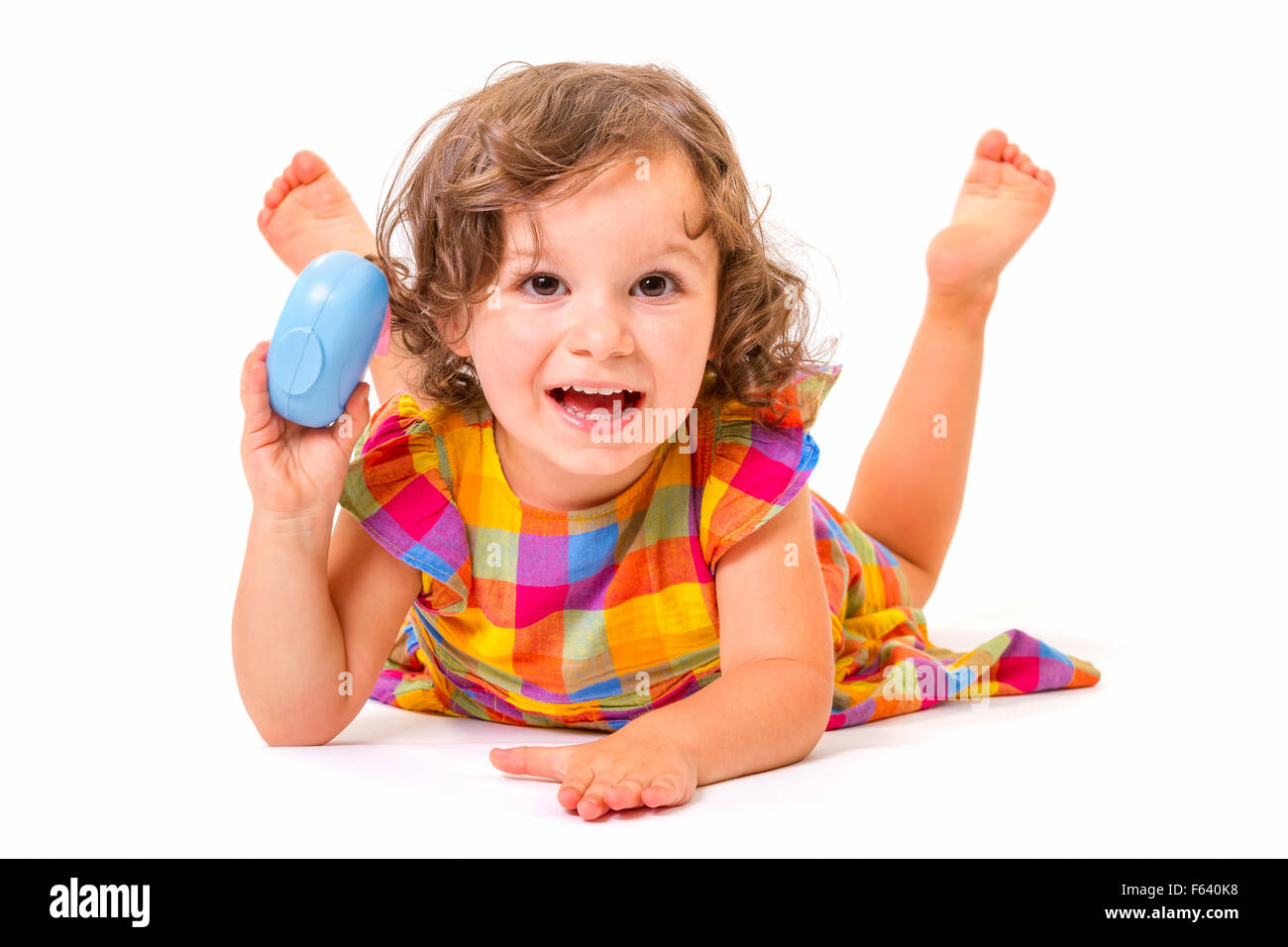 Cheerful little girl smiling at camera lying on white background. Stock Photo