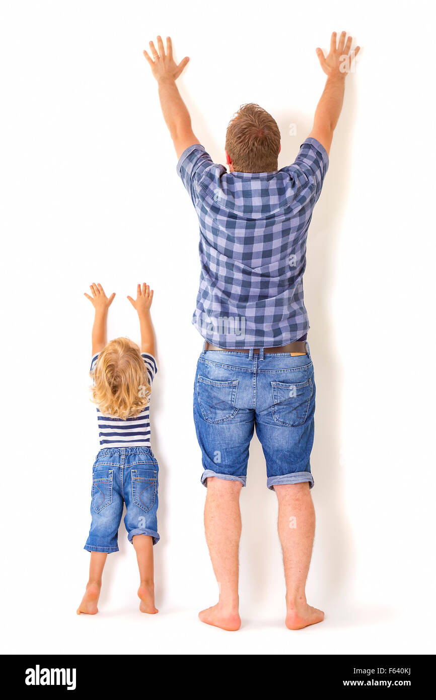 Father and son standing with their backs to the camera with hands up. Growing up concept. Stock Photo