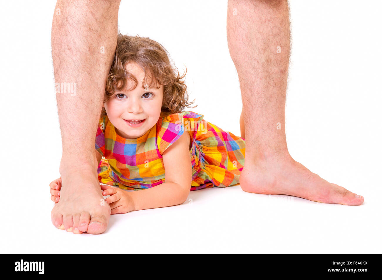 Little daughter feeling happy and protected at the feet of her father Stock Photo