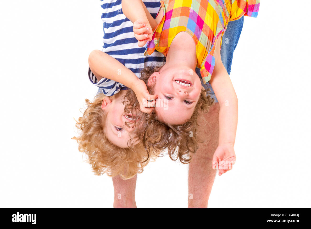 Father hands holding his smiling and playful children upside down on white background. Stock Photo