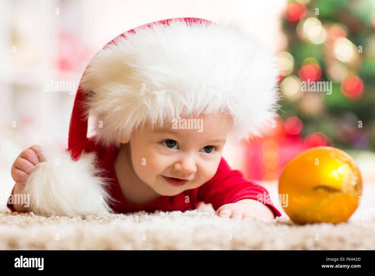 Funny baby in Santa Claus clothes with xmas tree Stock Photo