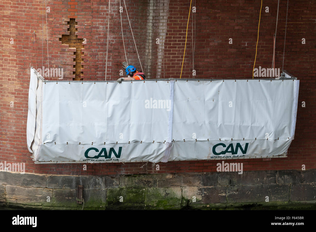 London, UK. 11 November 2015.  Construction workers at work on one of the exposed brick supports under Hungerford Bridge.  They are standing on a specially suspended platform with the River Thames a few feet below them and train tracks into Charing Cross railway station above them. Credit:  Stephen Chung / Alamy Live News Stock Photo