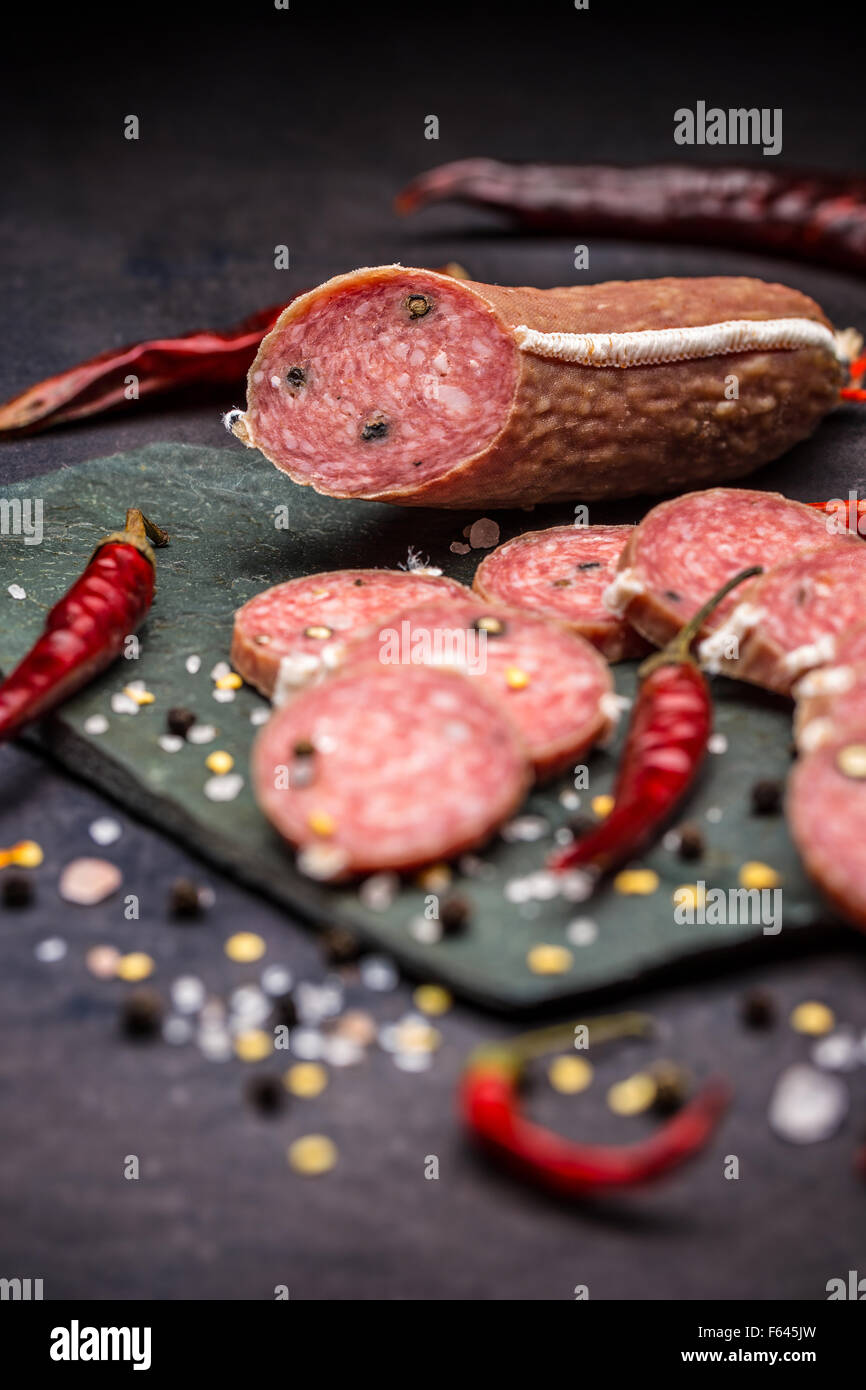 Sliced salami on black slate background Stock Photo