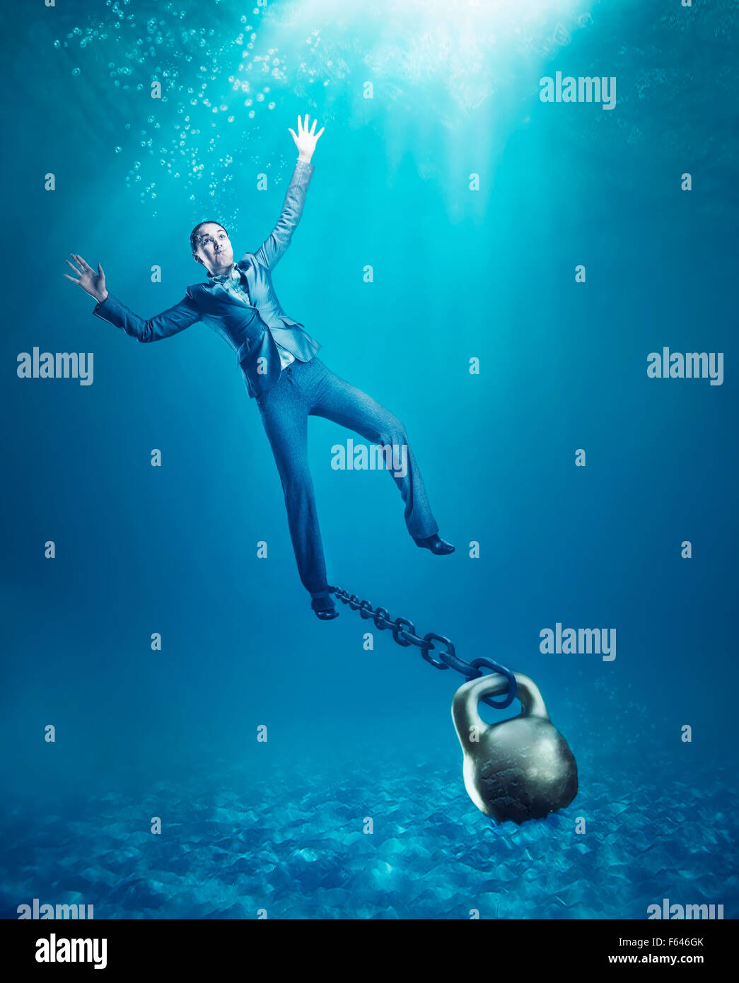 Businesswoman with dumb-bell on her hand sinking in the sea Stock Photo