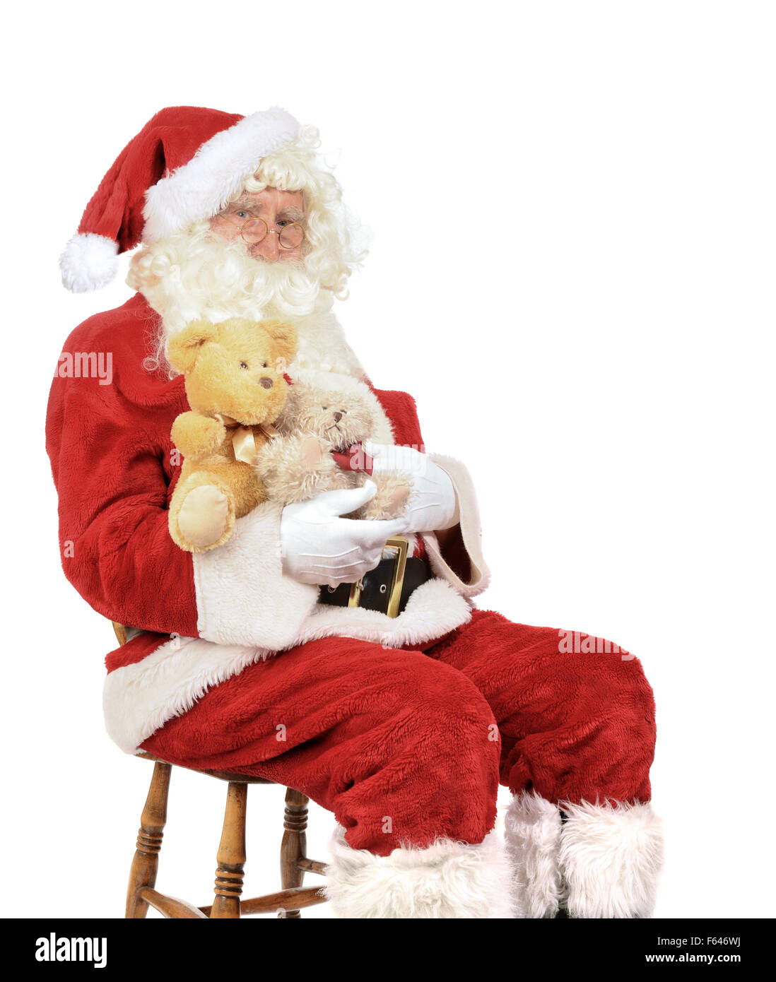 Santa Claus sitting in a chair holding teddy bears for Christmas Stock Photo