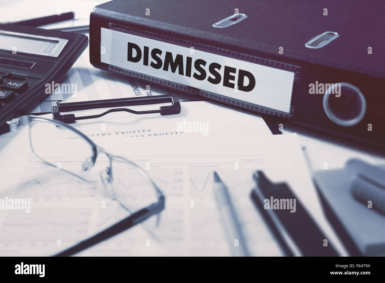 Ring Binder with inscription Dismissed on Background of Working Table with Office Supplies, Glasses, Reports. Toned Illustration Stock Photo