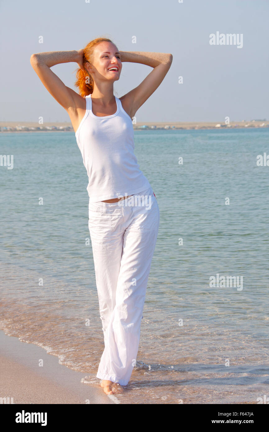 Attractive woman in white walking barefoot on the beach Stock Photo - Alamy
