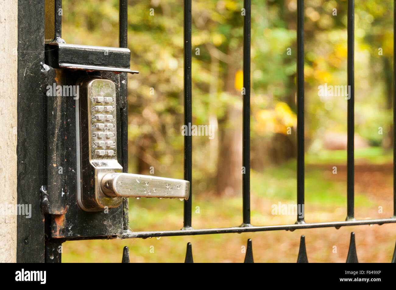 A lock with a keypad and security code on an outside gate leading to a country path. Stock Photo