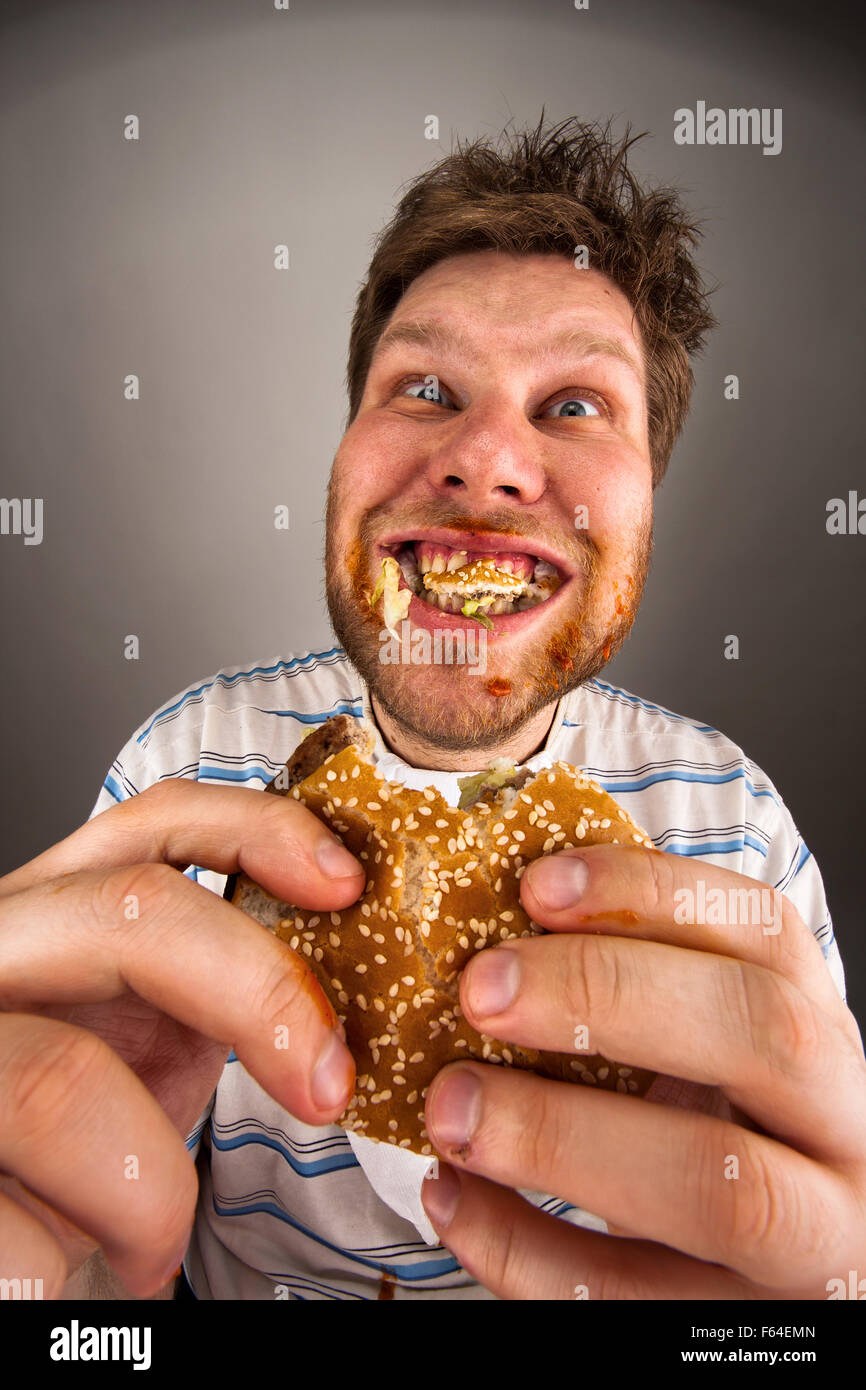 Portrait of expressive fat man chewing hamburger Stock Photo