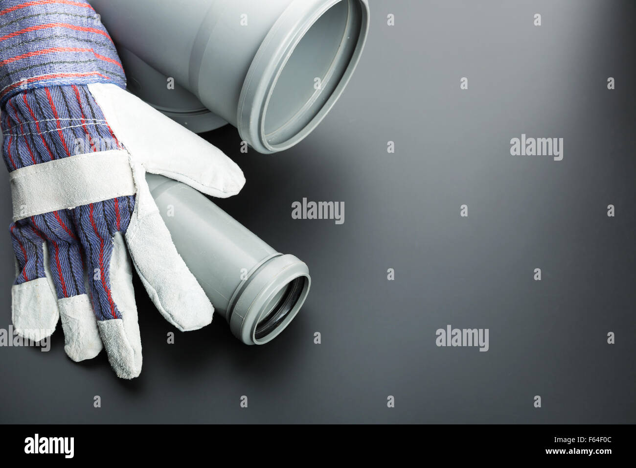 Soil-pipe and building glove on grey background Stock Photo