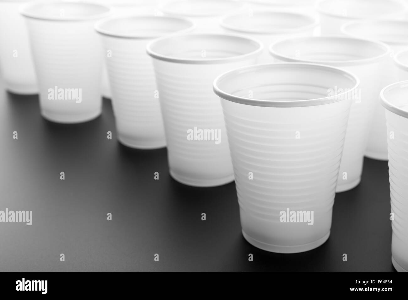 Lots of white plastic drinking glasses on grey background Stock Photo