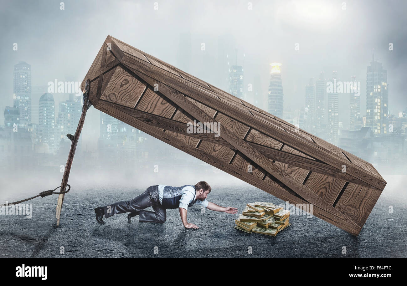 Businessman trying to get money under big wooden box trap Stock Photo