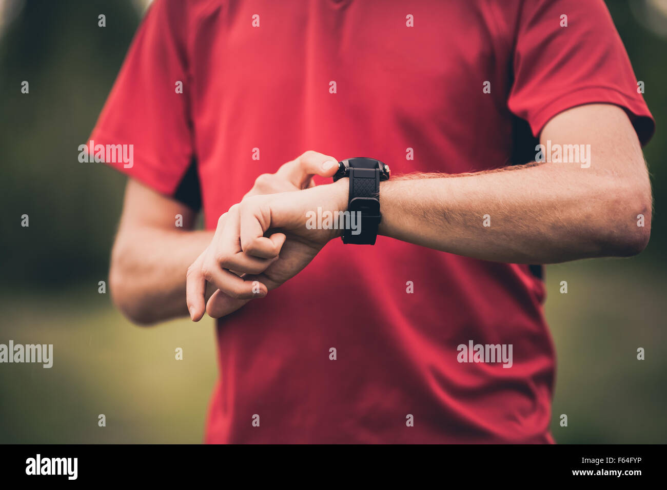 Runner using heart rate monitor training running, smartwatch checking performance or GPS. Man athlete looking at stopwatch. Stock Photo