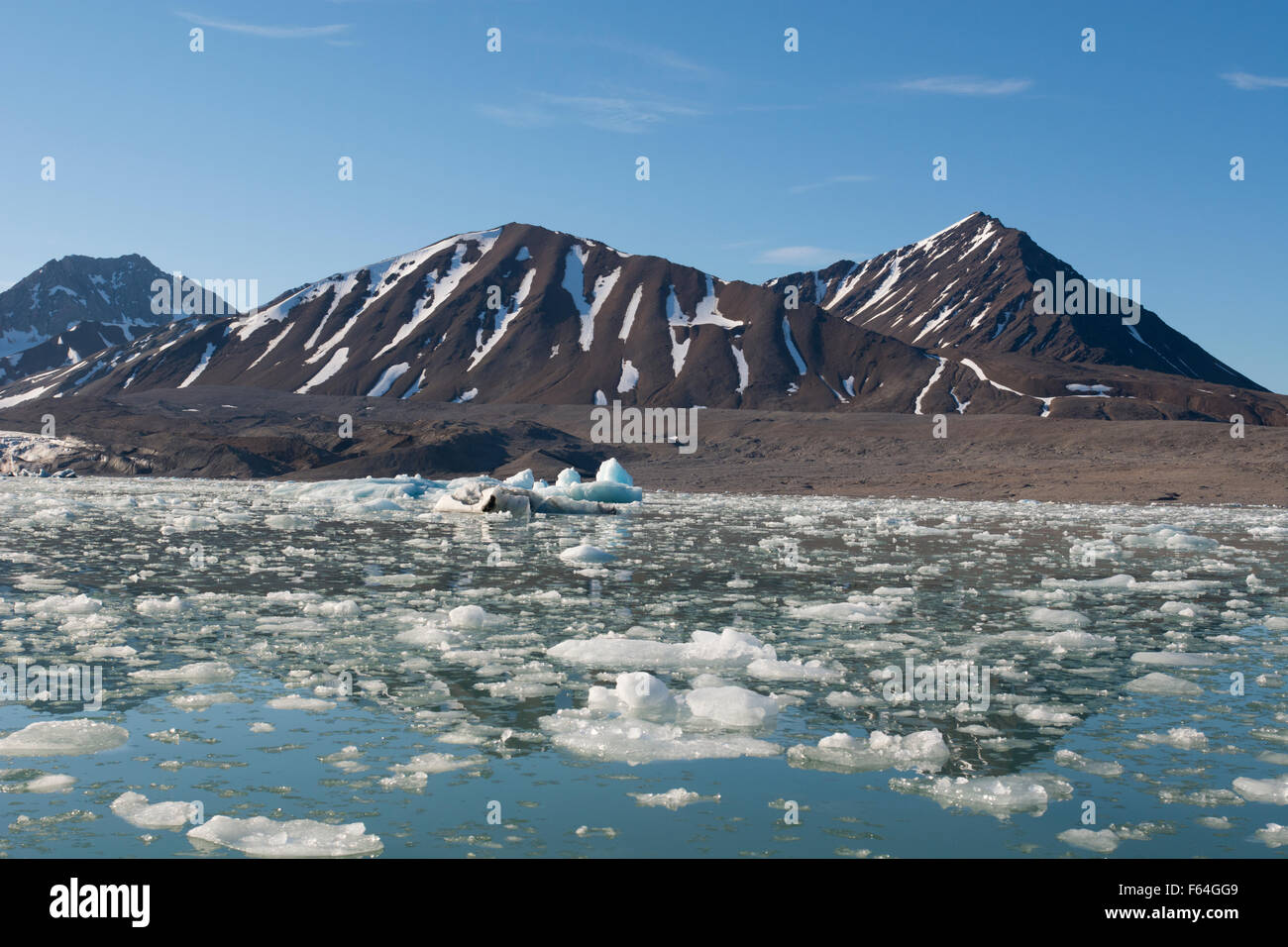 Norway, Barents Sea, Svalbard, Spitsbergen. Calm bay and mountain landscape in front of 14th July Glacier. Stock Photo