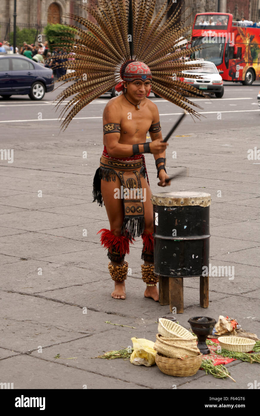 Conchero dancer wearing a feathered headdress beating a drum in downtown Mexico City Stock Photo