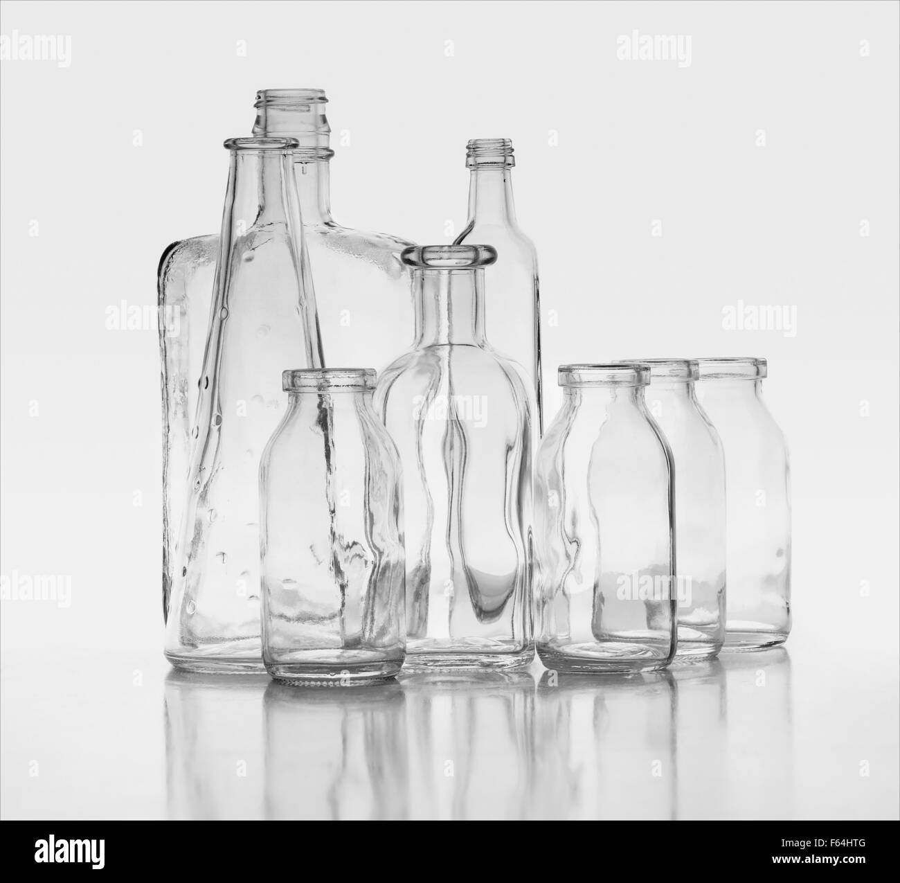 8 delicately photographed black and white glass bottles floating on horizon showing refraction and bending of light.  ethereal Stock Photo