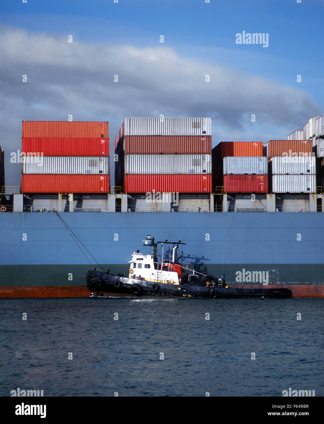 California, Long Beach Harbor, Tugboat guiding cargo ship Stock Photo