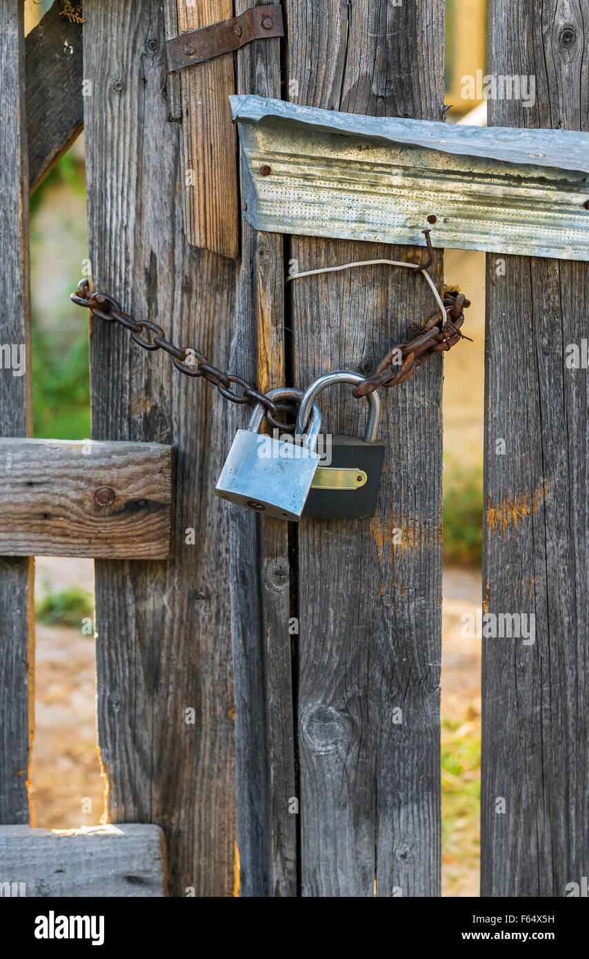 Wooden gates closed with a chain with double lock Stock Photo - Alamy