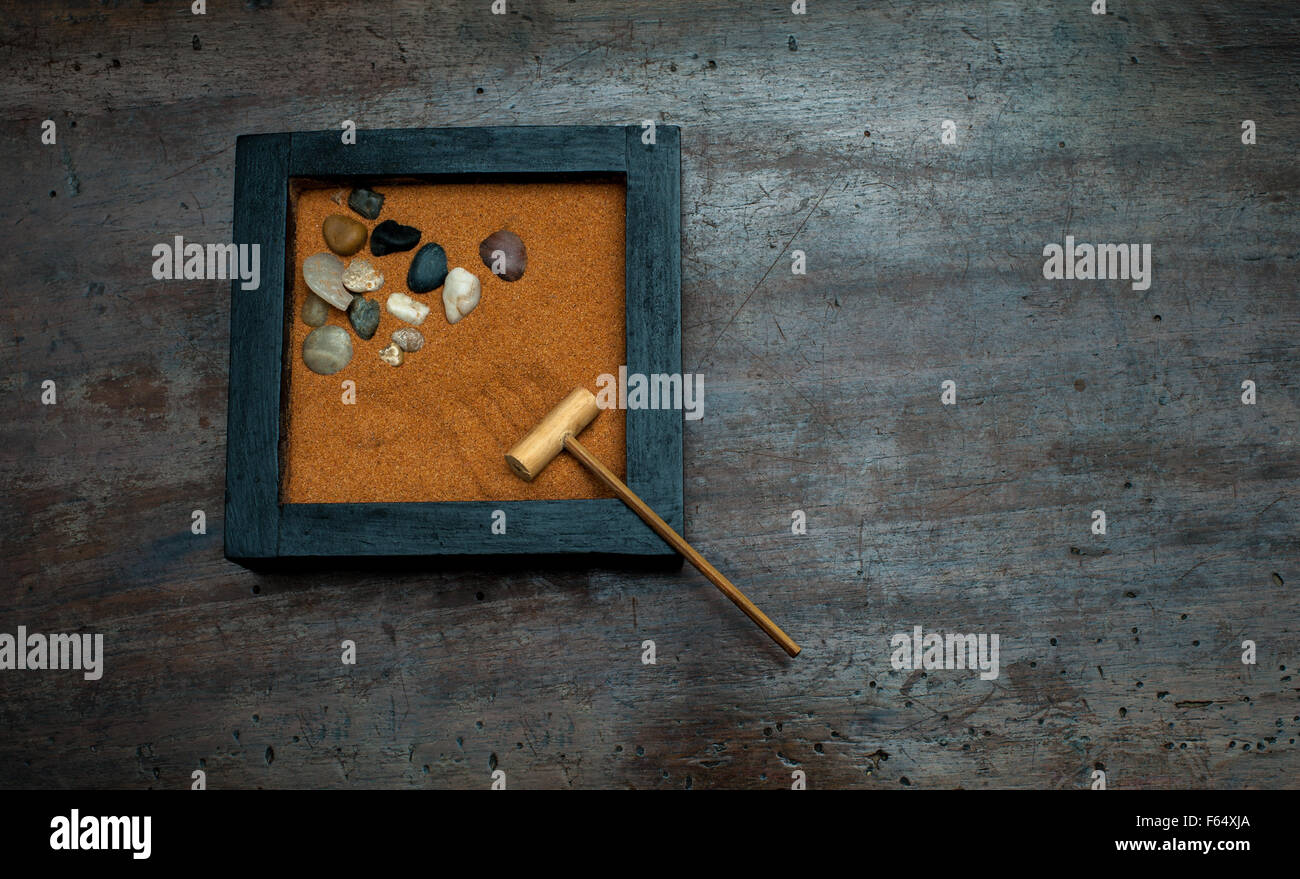 Zen garden with rake and stones, orange sand on aged scraped wood Stock