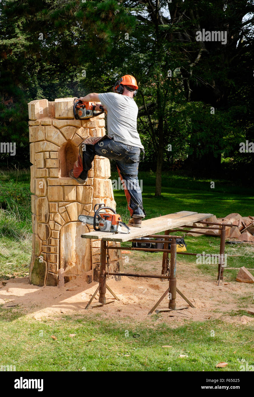 A chainsaw sculptor creating a tower sculpture from a tree trunk at the Cranborne Chase Woodfair, Wiltshire, UK Stock Photo