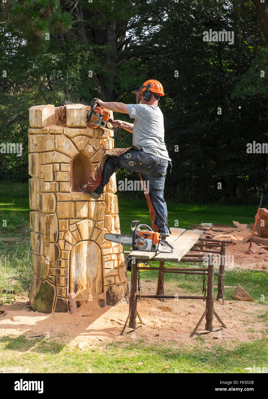 A chainsaw sculptor creating a tower sculpture from a tree trunk at the Cranborne Chase Woodfair, Wiltshire, UK Stock Photo