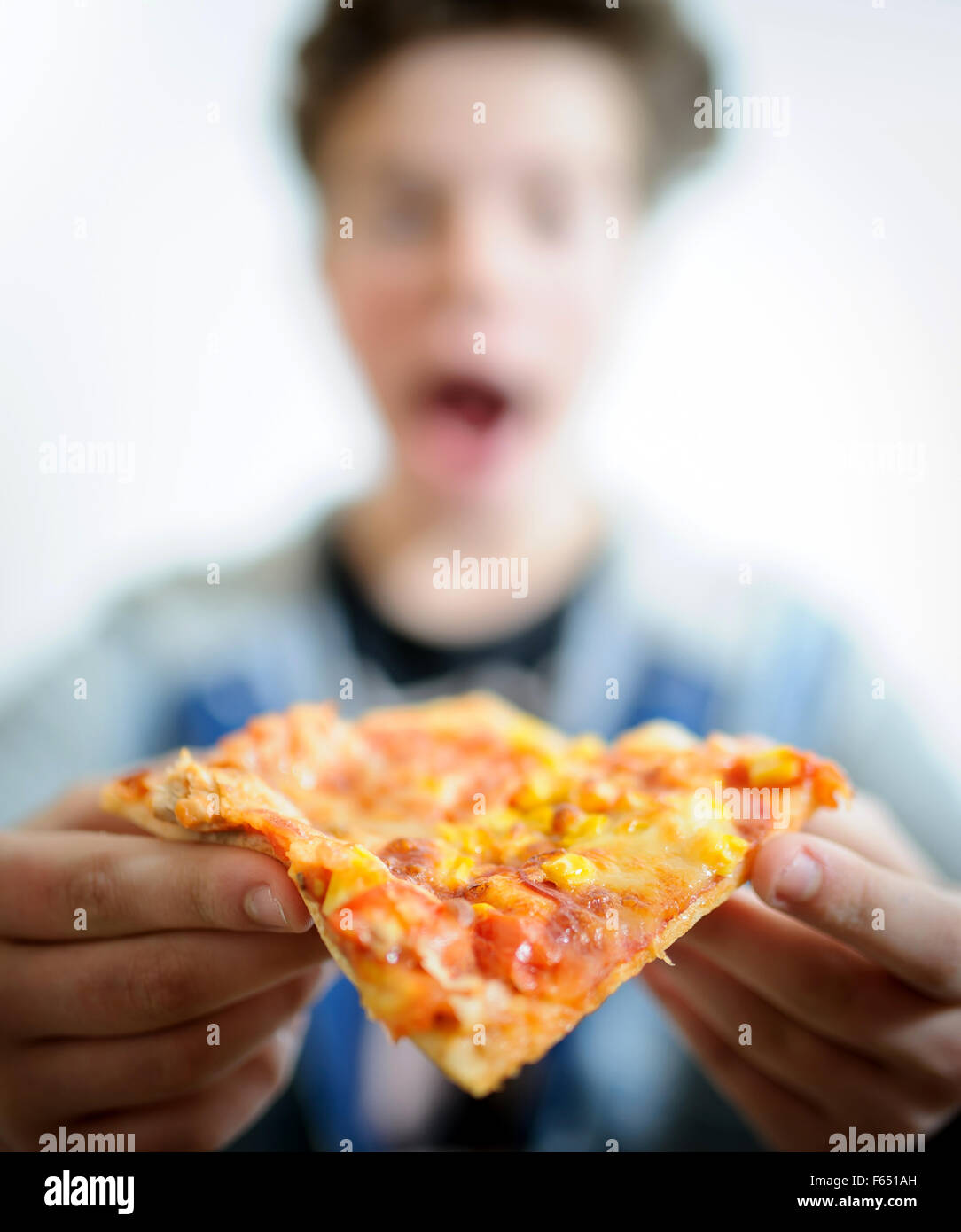 ILLUSTRATION - A boy wants to take a bite of a pizza. The photo was taken on 06 January 2015 in Dresden (Saxony). Photo: Thomas Eisenhuth Stock Photo