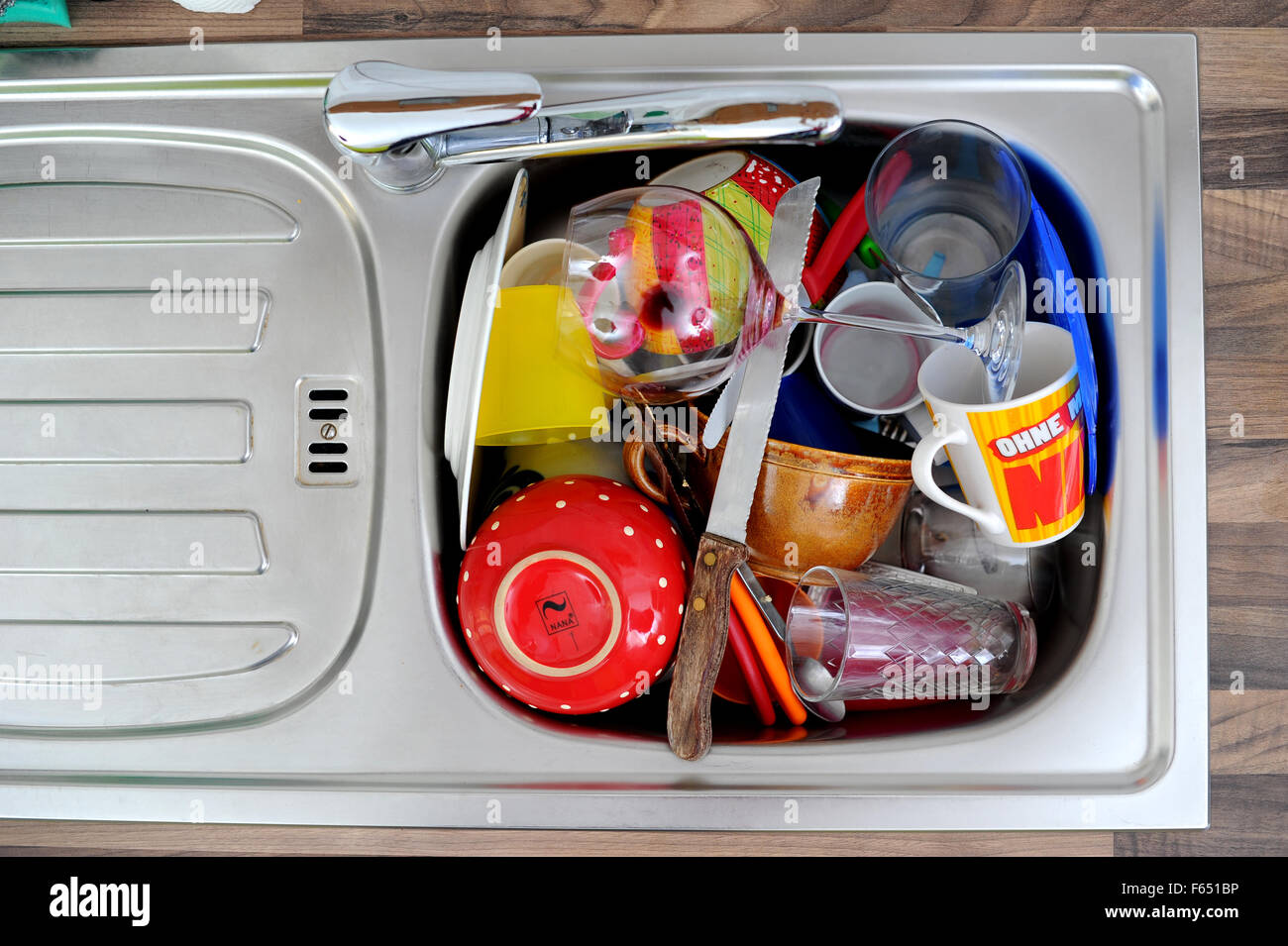 In a kitchen sink, dirty dishes are piling up. The photo was taken on 19 March 2013 in Dresden (Saxony). Photo: Thomas Eisenhuth Stock Photo