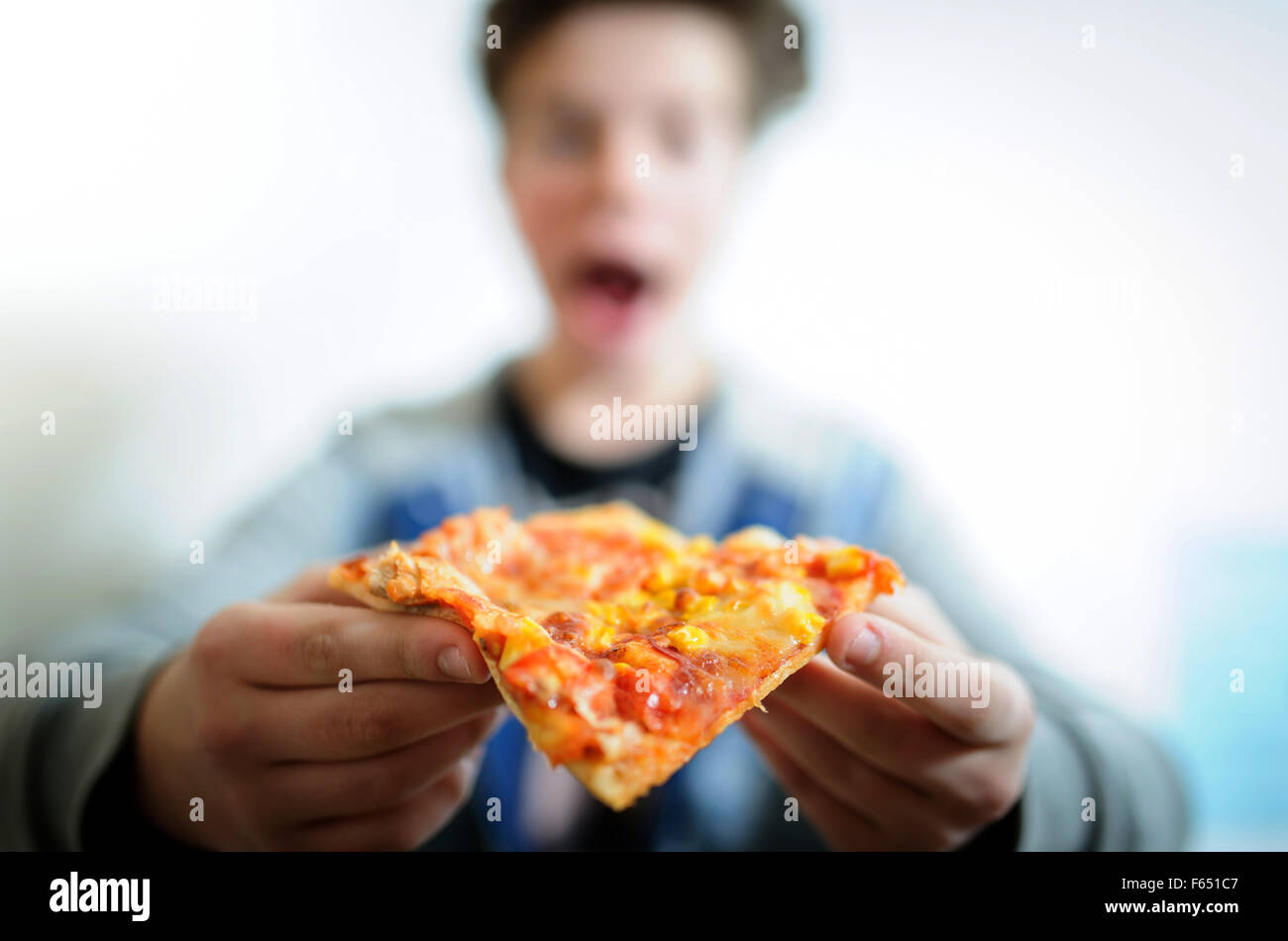 ILLUSTRATION - A boy wants to take a bite of a pizza. The photo was taken on 06 January 2015 in Dresden (Saxony). Photo: Thomas Eisenhuth Stock Photo