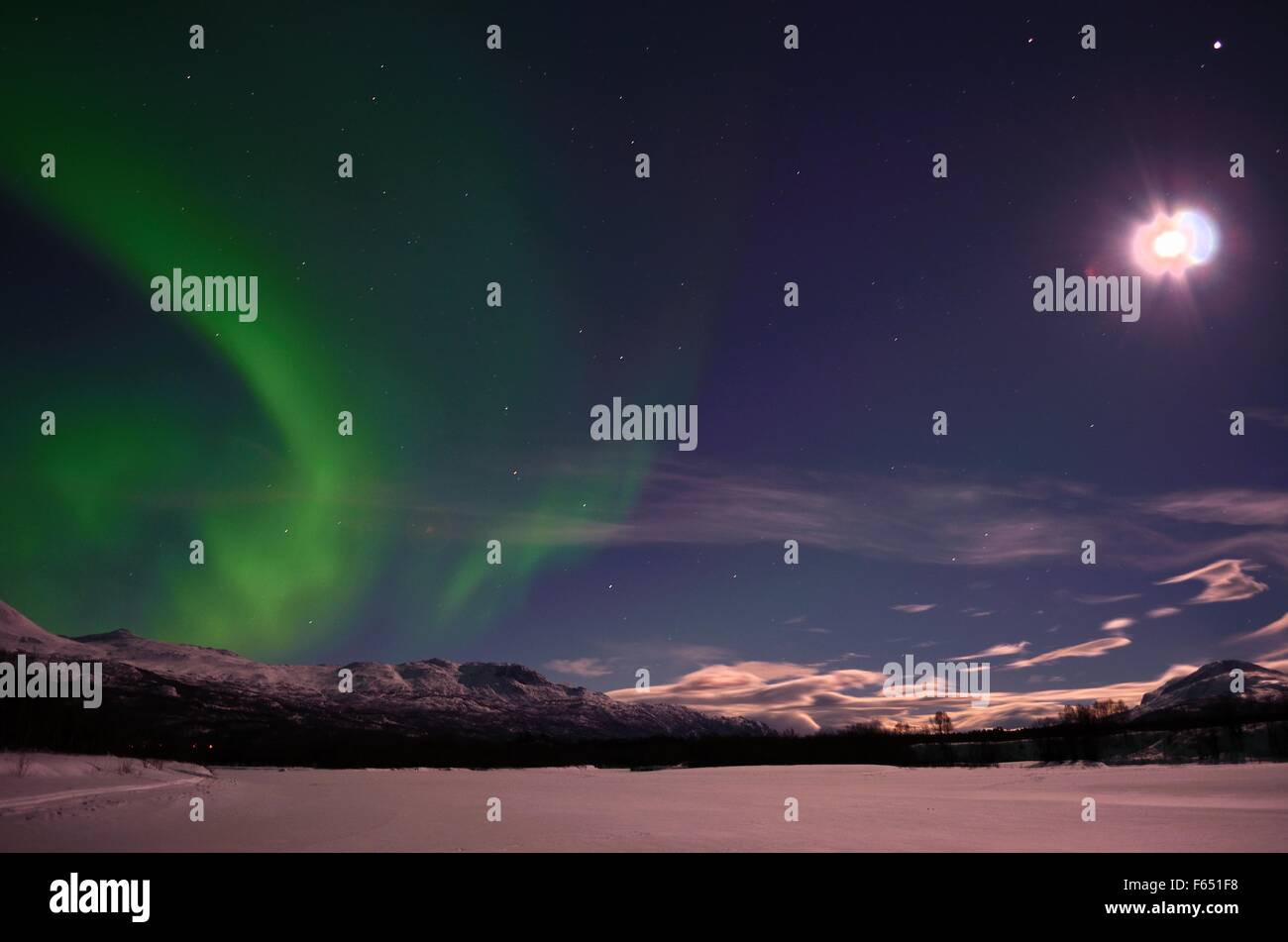 Aurora borealis on arctic winter night over snowy mountain on a frozen ...