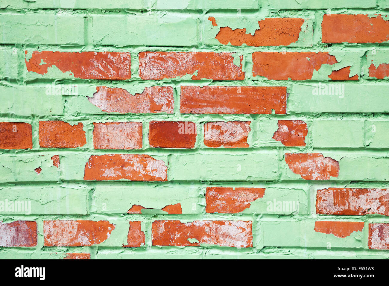 Old brick wall closeup texture with damaged layer of green paint