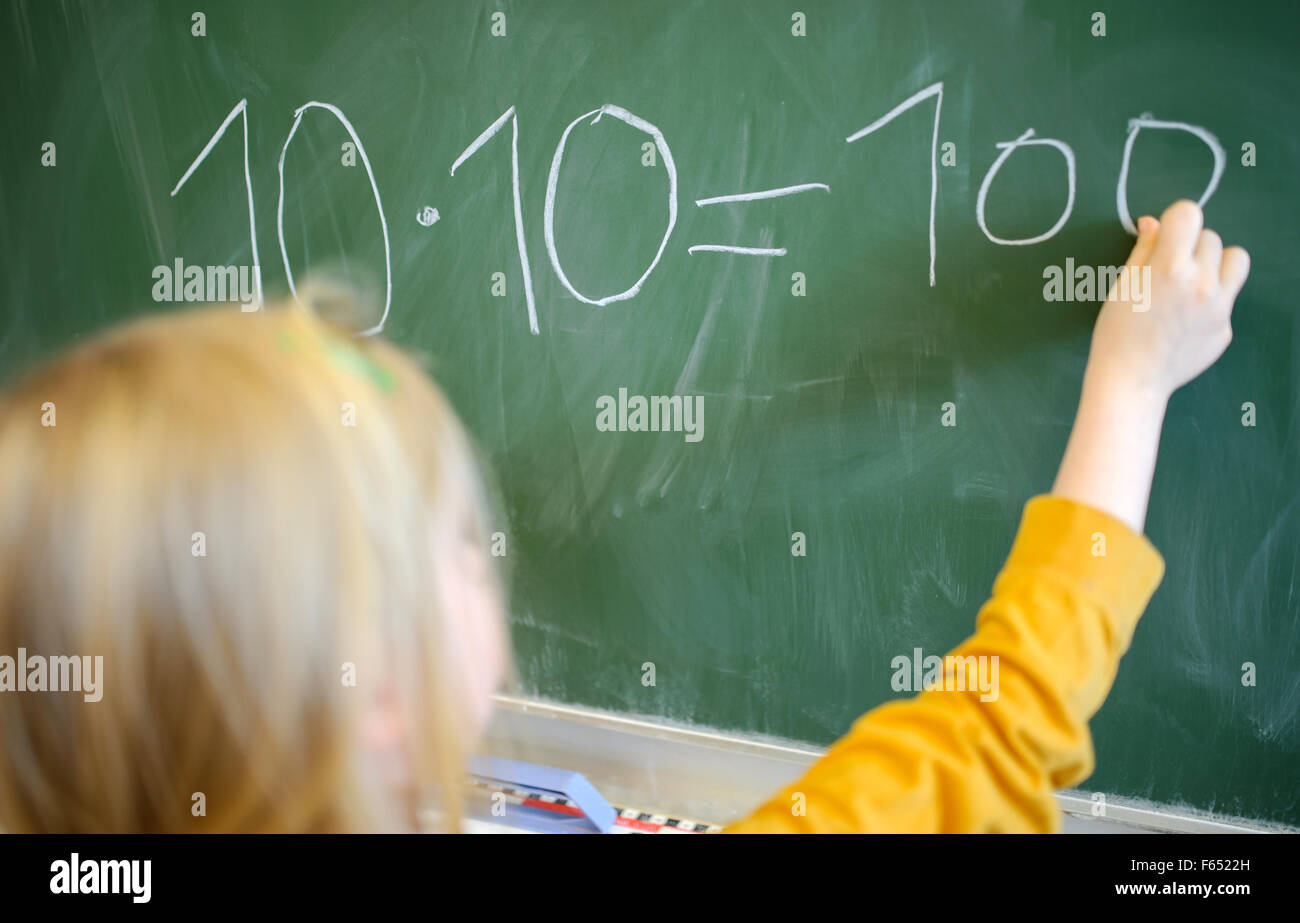 A girl writes a math exercise (10 x 10 = 100) on a blackboard with sidewalk chalk in Dresden (Saxony), Germany, 19 January 2015. Photo: Thomas Eisenhuth Stock Photo