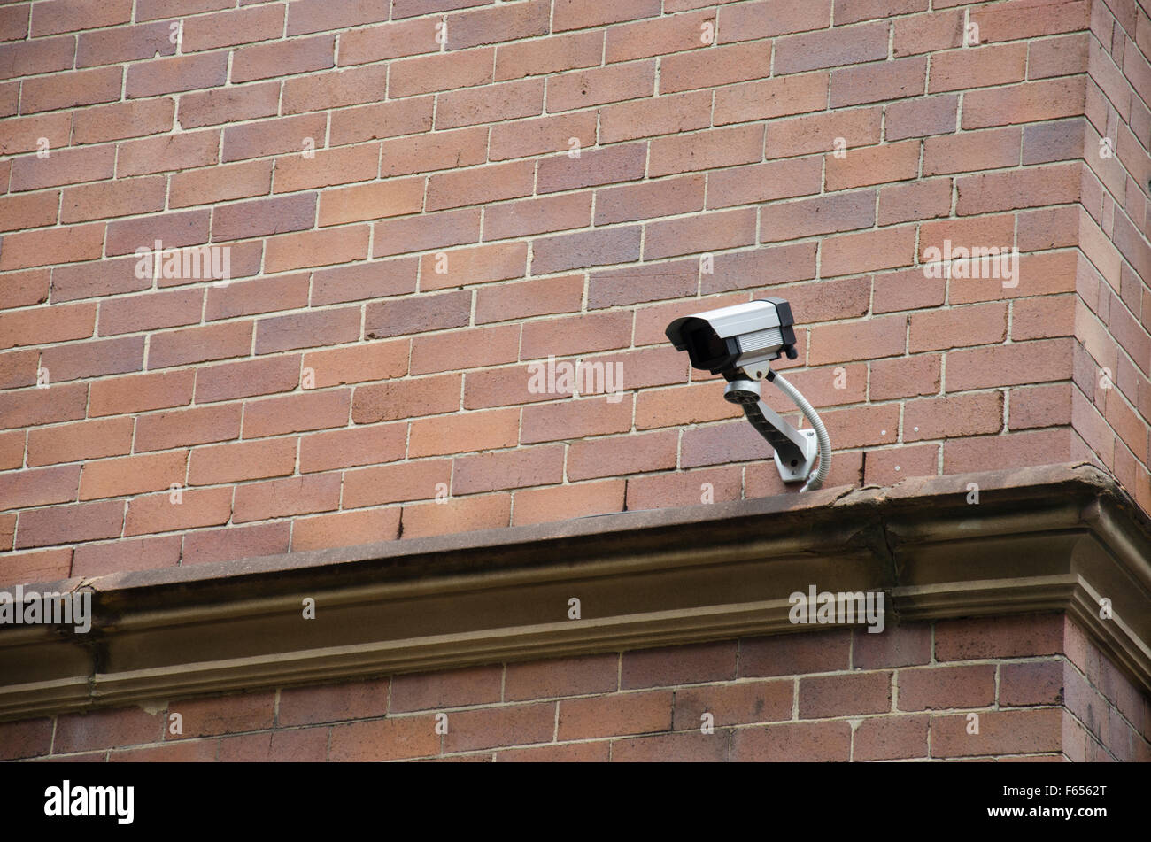 A surveillance or security CCTV camera mounted high on an exterior wall